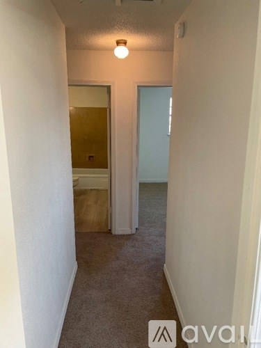 A hallway with a carpeted floor and a light on the ceiling.