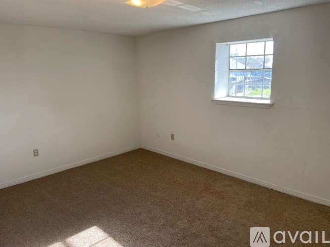 A room with a carpeted floor and a window letting in natural light.