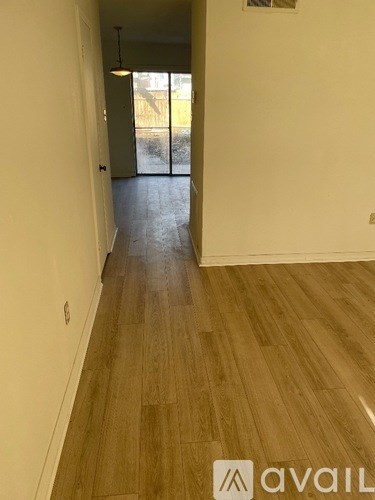 A hallway with wooden floors and white walls.