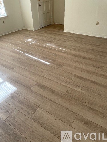 A room with wooden flooring and a door in the background.