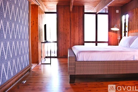 A bedroom with a bed, wooden walls, and a window.