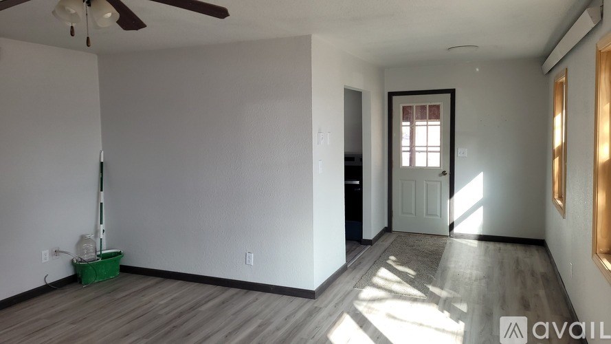 A room with a ceiling fan and a vacuum cleaner on the floor.