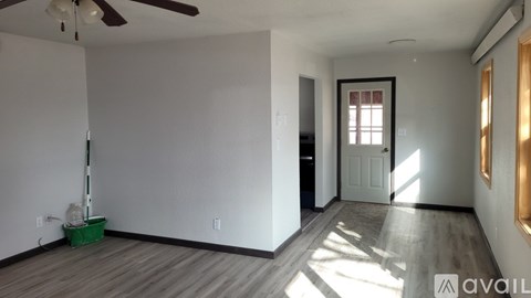 A room with a ceiling fan and a vacuum cleaner on the floor.