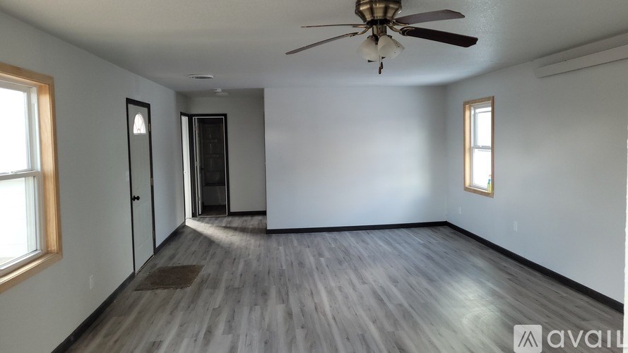 A room with a ceiling fan and wooden flooring.