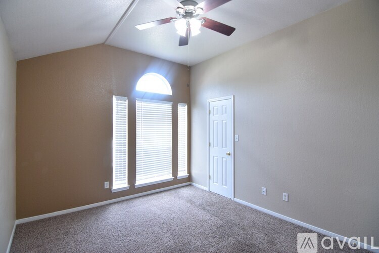 A room with a ceiling fan and a window with blinds.
