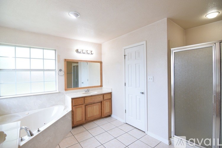 A bathroom with a tub, sink, mirror, and a white door.
