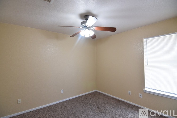 A room with a ceiling fan and a window with blinds.