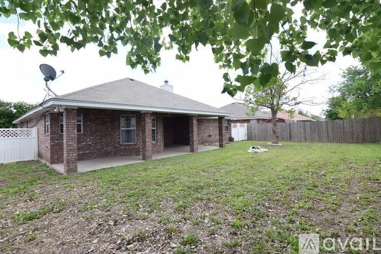 A house with a satellite dish on the roof and a fence in the yard.