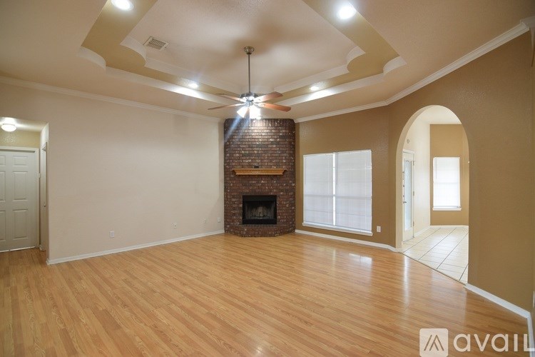 A spacious room with a fireplace and wooden flooring.