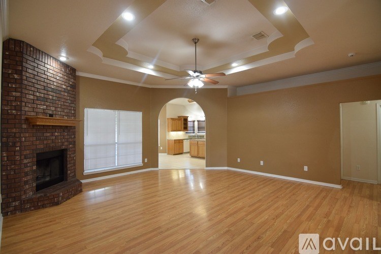 A spacious room with a brick fireplace and wooden flooring.