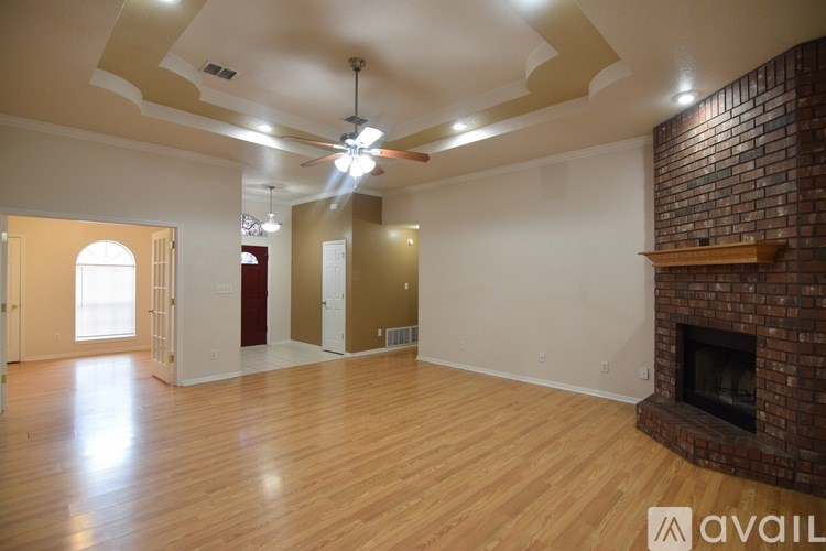 A large empty room with wooden floors and a brick fireplace.
