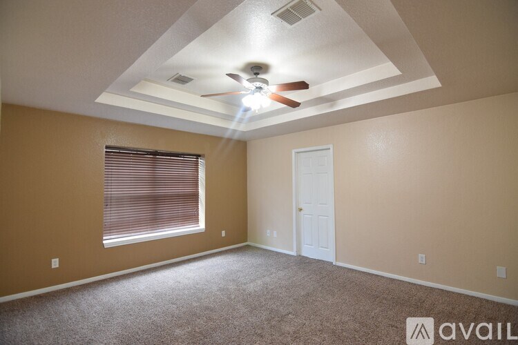 A room with a ceiling fan and a window with blinds.