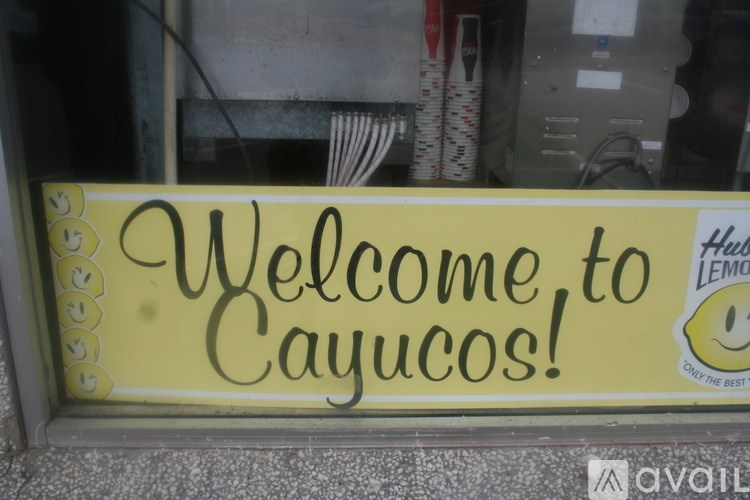 A yellow sign that says "Welcome to Cayucos!" is displayed.