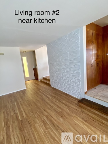 A living room with wooden floors and a white wall.
