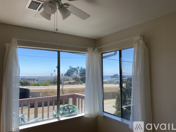 A room with a fan and a window overlooking a balcony.