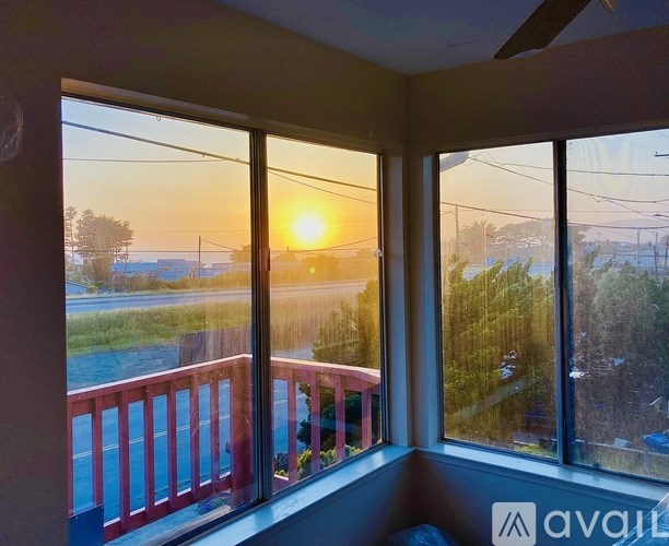 A sunset view from a room with a balcony.