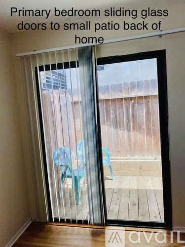 A patio with a sliding glass door leading to a backyard.
