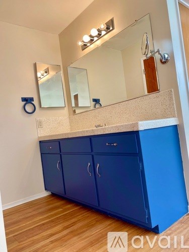 A bathroom with blue cabinets and a mirror above the sink.