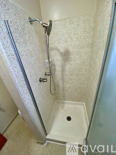 A shower stall with a glass door and a white floor drain.