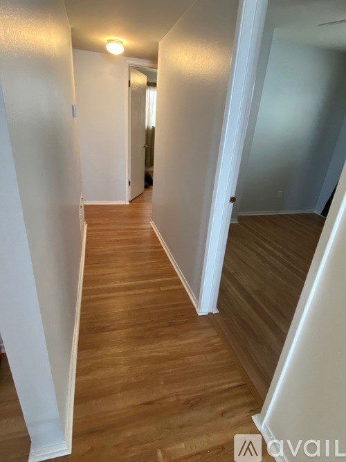 A long hallway with wood floors and white walls.