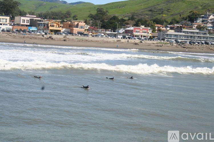 A beach scene with surfers and buildings in the background.