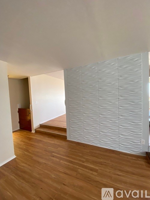 A room with wooden floors and a white wall with a patterned panel.