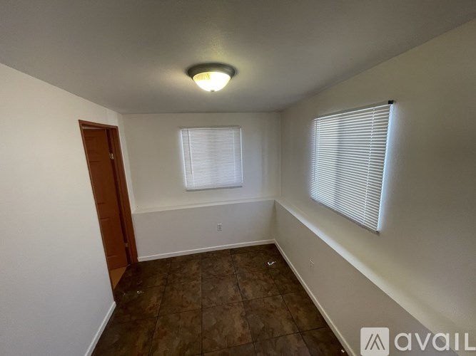 A room with a brown tile floor and a window with blinds.
