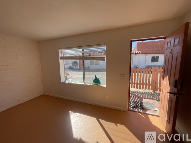 A room with a window overlooking a balcony with a person sitting on a chair.