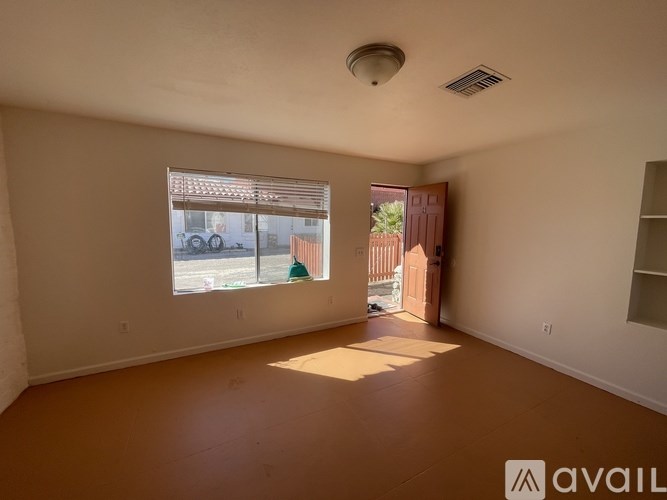 A room with a large window and a view of a street with cars and buildings.