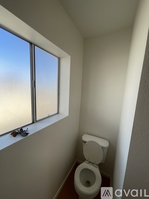 A white toilet in a small bathroom with a window.