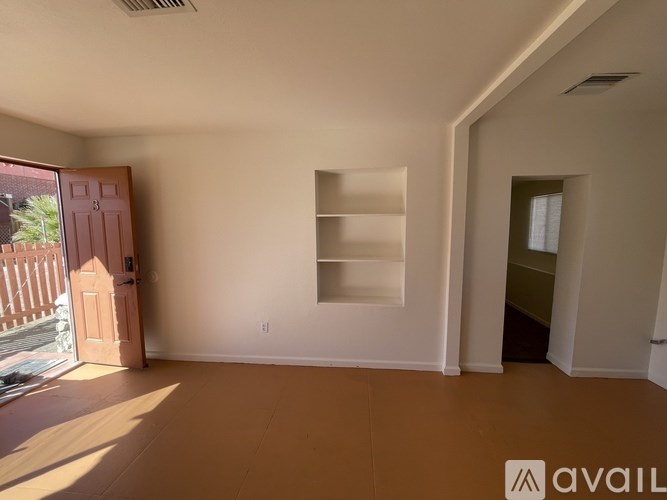 A room with a wooden floor, a white wall, and a shelf is available for rent.