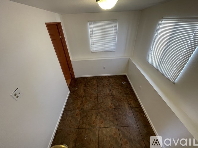 A room with a brown tile floor and a window with blinds.