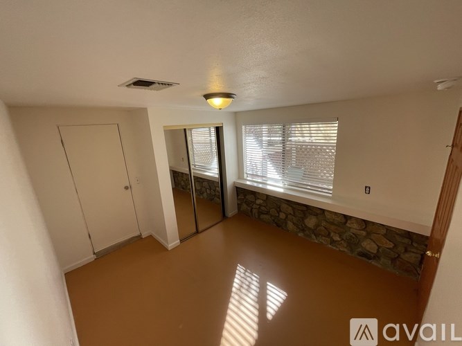 A room with a stone wall and a window with blinds.