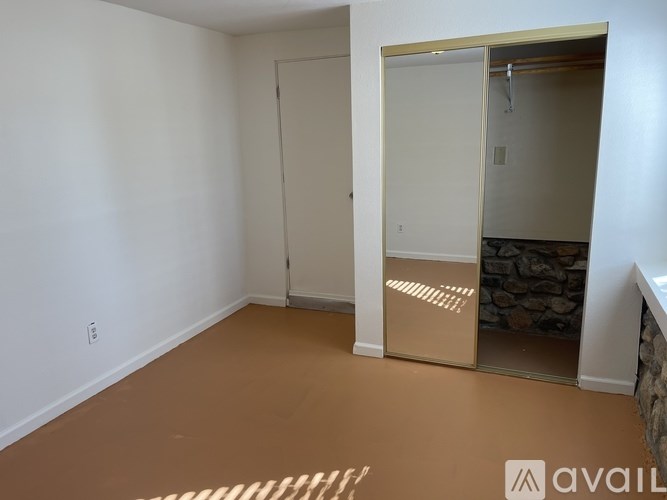 A room with a white door and a brown floor.