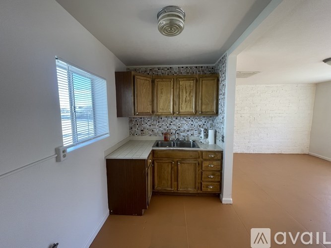 A kitchen with wooden cabinets and a tiled backsplash is available for rent.