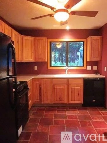 A kitchen with wooden cabinets and a black fridge.