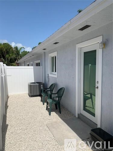 A white house with a green chair and a white fence.