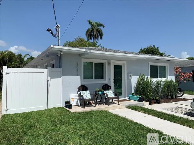 A white house with a green lawn in front.
