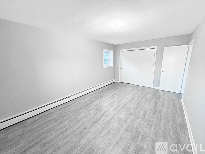 A spacious room with grey flooring and white walls.