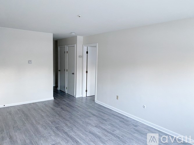 A room with a grey floor and white walls with a doorway leading to another room.