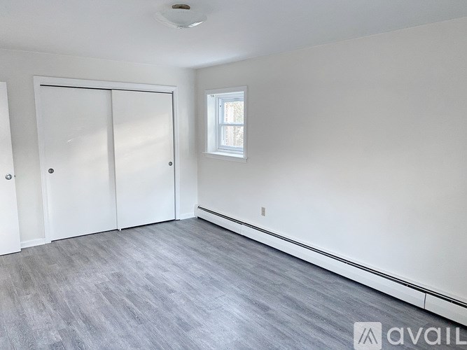 A room with a white door, a window, and a grey floor.