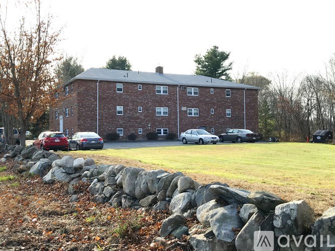 A large red brick building with a stone wall in front.