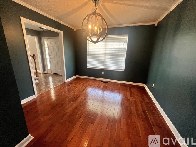 A room with wooden flooring and a chandelier hanging from the ceiling.