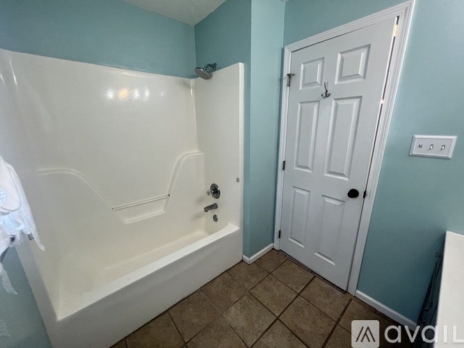 A white bathtub with a shower head and a white door in a room.