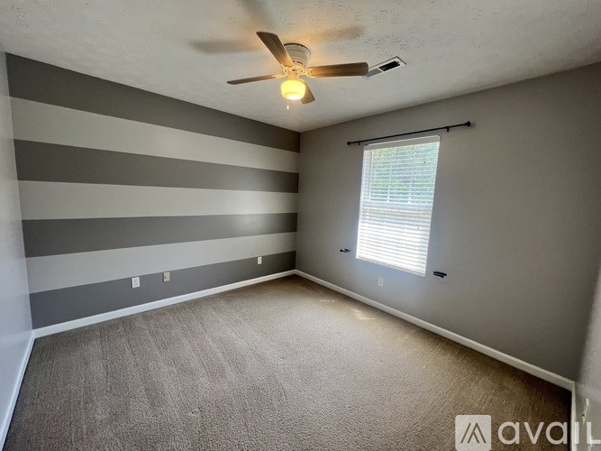 A room with a ceiling fan and striped walls.