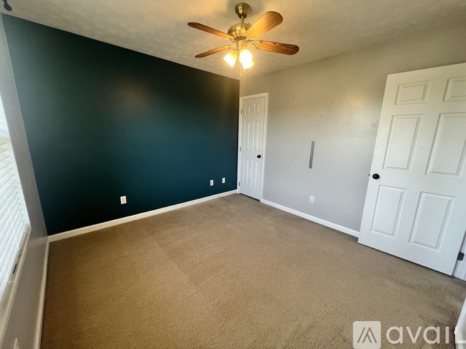 A room with a ceiling fan and carpeted floor.