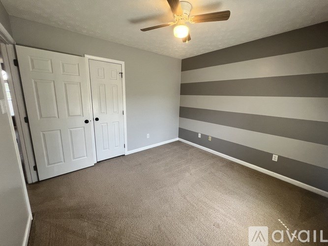 A room with striped walls and a ceiling fan.
