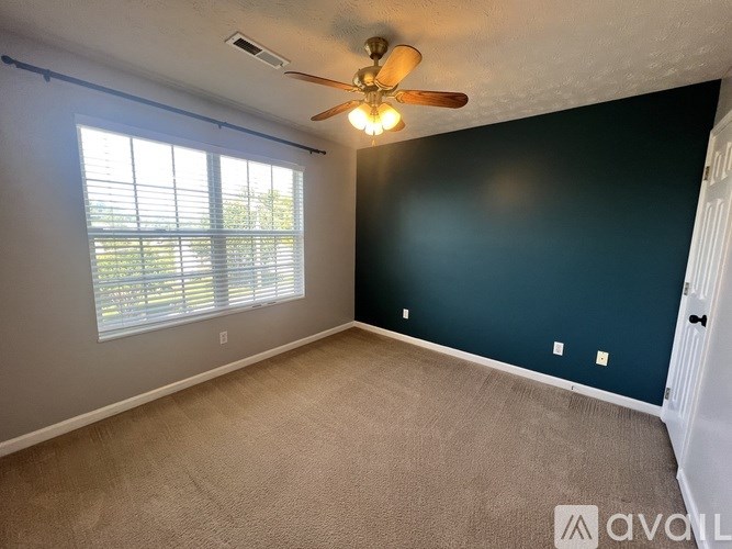 A room with a ceiling fan and a window with blinds.