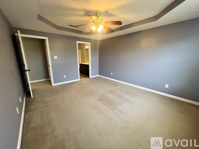 A spacious room with a ceiling fan and two doors.