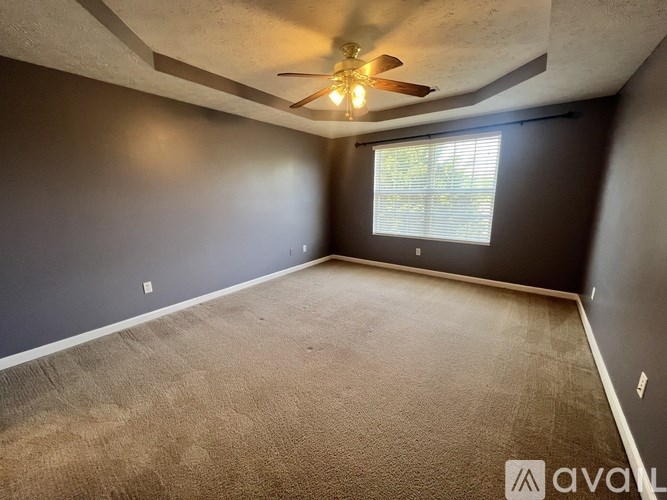 A room with a ceiling fan and a window with blinds.